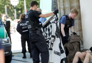 A German police officer looks at a banner belonging to members of far right Identitarian movement  after the activists staged a demonstration on top of Brandenburg Gate in Berlin